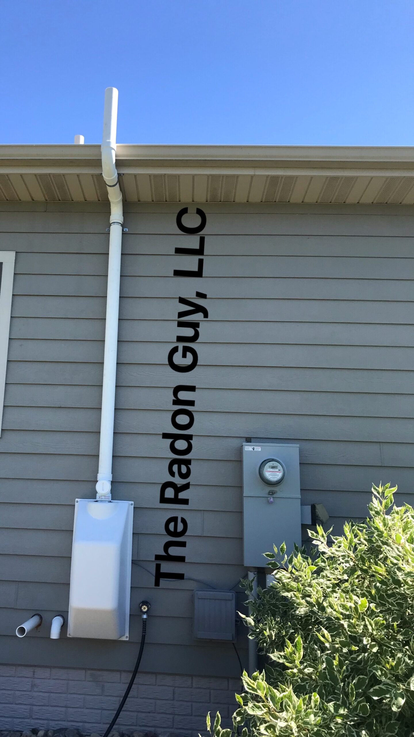 exterior radon mitigation system with cover on fan installed by The Radon Guy.